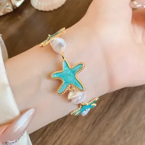 Detailaufnahme eines goldfarbenen Armbands mit türkisen Seesternen und Perlenelementen