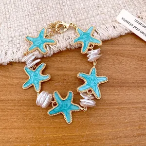 Nahaufnahme eines Armbands im Strandstil mit blauen Seesternen und weißen Perlen.