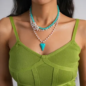 Primo piano di una collana di perle a strati con ciondolo a cuore e dettaglio floreale