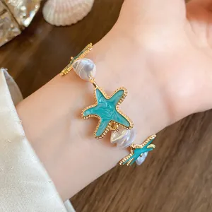 Detailansicht eines blauen Emaille-Seestern-Armbands mit weißen Barockperlen am Handgelenk