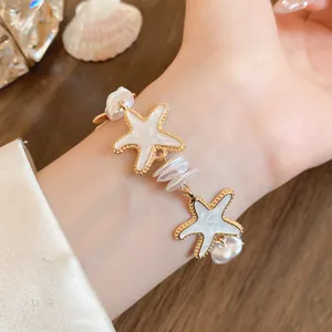 Detailansicht eines eleganten Armbands mit goldumrandeten Seesternen und Perlen