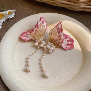 Elegant close-up detail of embroidered butterfly earrings featuring long pearl tassels
