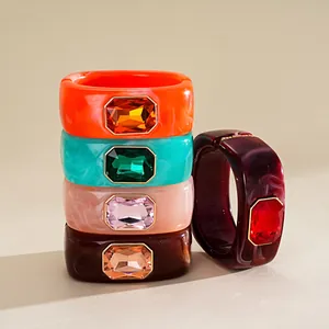 Dettaglio di bracciali colorati in resina con grandi cristalli rettangolari