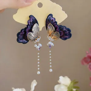 Detailed view of embroidered butterfly earrings with zircon accents and long pearl tassels