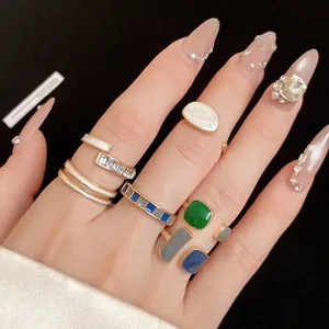Dettaglio di eleganti anelli regolabili in smalto e cristallo su mano femminile