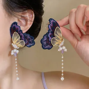 Close-up of elegant purple embroidery butterfly earrings with long pearl tassels