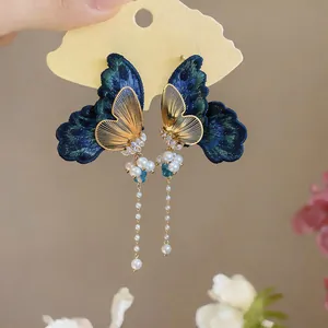 Detailed view of elegant embroidered butterfly earrings with zircon and pearl tassels.