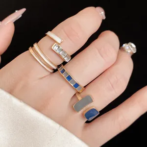 Primo piano di eleganti anelli impilabili in smalto dorato con dettagli blu e bianchi