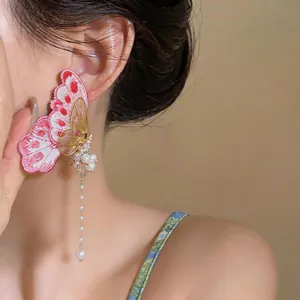 Detailed macro view of an elegant embroidery butterfly earring featuring long pearl tassels.