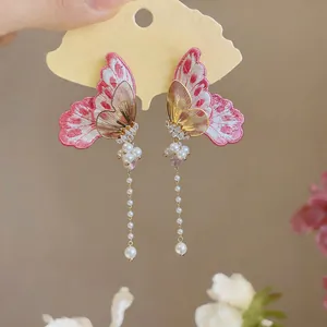Detailed view of embroidered butterfly earrings with pearl tassels and zircon accents