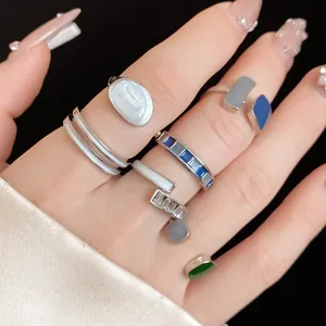 Primo piano di vari anelli colorati in smalto indossati su una mano con manicure.