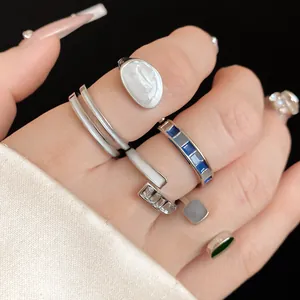 Primo piano di vari anelli d'argento minimalisti con dettagli in smalto e pietre su mano.