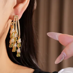 Detail view of 18k gold plated earrings with green and white zircon teardrop tassels