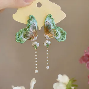 Detailed view of elegant green embroidered butterfly earrings with long pearl tassels