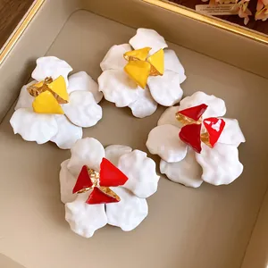 Detailed view of vintage flower stud earrings with red and yellow enamel centers