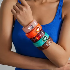 Vista dettagliata di bracciali in resina colorata impilati con grandi gemme.