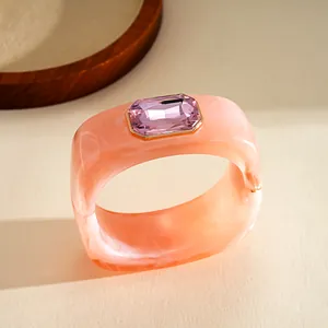 Dettaglio ravvicinato del bracciale geometrico quadrato in resina rosa con gemma viola