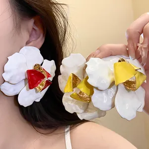 Detailed close-up of oversized enamel flower earrings in white, red, and yellow