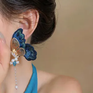 Detail view of blue embroidered butterfly earrings with pearl tassels and zircon accents