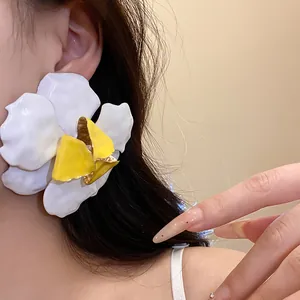 Close-up of a large white and yellow flower stud earring worn by an elegant Asian model.