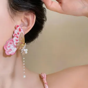 Close-up of embroidered butterfly earring with pearl tassel detail on model