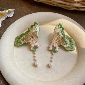 Detailed view of green embroidered butterfly earrings with elegant pearl tassels