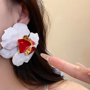Close-up view of an elegant white and red flower earring featuring gold metallic details