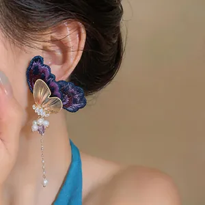 Elegant detail of embroidered butterfly earring featuring zircon and pearl tassels