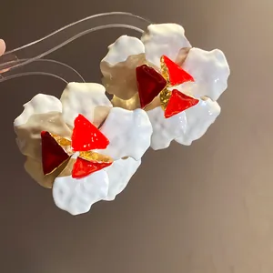 Macro view of vintage white and red floral stud earrings with premium enamel finish