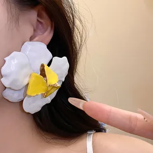 Close-up of retro white and yellow flower earrings with metallic oil-dripping texture