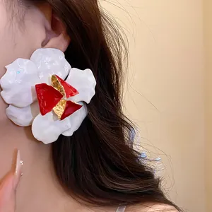 Detailed macro view of a large vintage white and red enamel flower stud earring on an ear