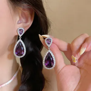Detail shot of elegant teardrop earrings with purple zirconia and sparkling pave stones
