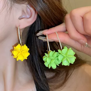 Détail de boucles d'oreilles fleurs élégantes avec pétales jaunes, verts et strass