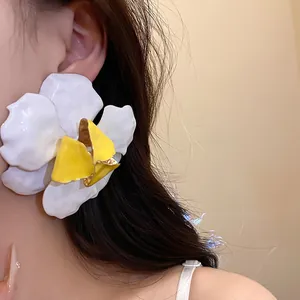 Close-up detail of large white and yellow enameled flower stud earring on a model's ear