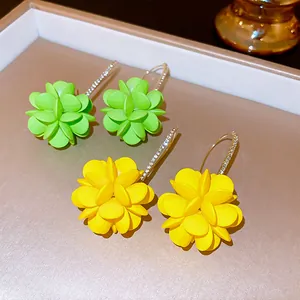 Vue détaillée de boucles d'oreilles fleurs vert et jaune avec des crochets en strass