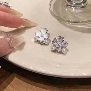 Elegant asymmetric flower stud earrings with shimmering pearls and rhinestones on a plate
