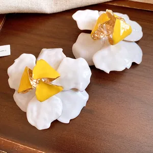 Macro view showing the detailed texture of vintage-style white and yellow floral stud earrings