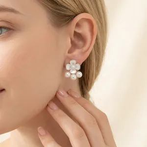 Elegant white flower stud earrings with pearls and rhinestones worn on an Asian model
