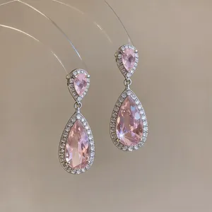 Detailed close-up of pink teardrop zircon earrings featuring a halo of small crystals