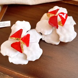 Close-up of white and red enamel flower earrings with elegant golden accents