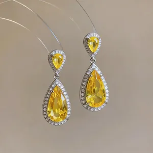 Detail view of luxury silver-tone teardrop earrings with brilliant yellow zircons.