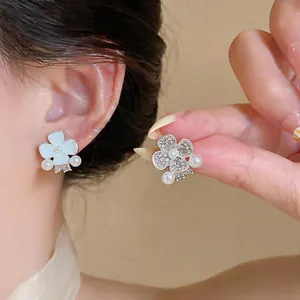 Close-up detail of sweet asymmetric flower stud earrings with pearls and sparkly rhinestones