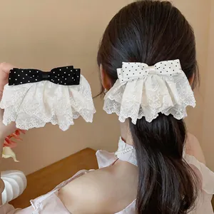 Detail showing elegant polka dot lace bow hair clips in classic black and white colors.