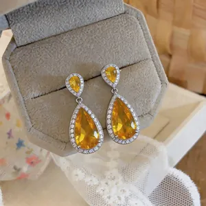 Detailed close-up of luxurious yellow water drop zircon earrings in a silver halo setting