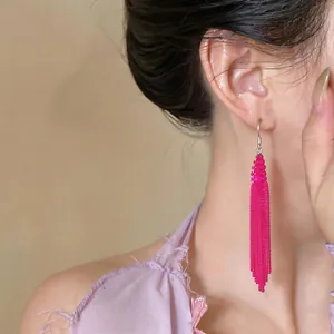 Detailed view of vibrant magenta beaded tassel drop earrings worn on a model's ear