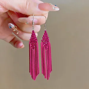 Detailed view of magenta beaded rhombus earrings with long chain tassels