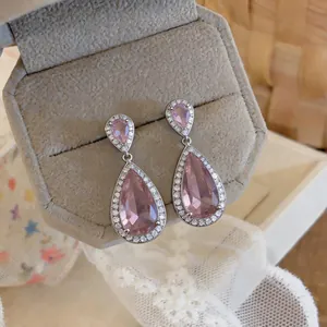 Close-up view of elegant pink teardrop zircon dangle earrings in a velvet box