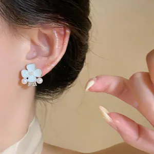 Detail of sweet flower stud earring with pearls and sparkling crystals on model ear.