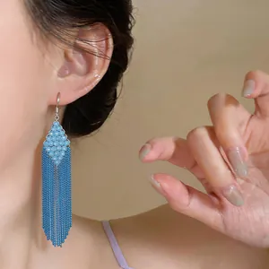 Close-up detail of blue beaded diamond earrings with long elegant chain tassels