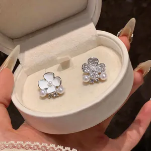 Close-up of asymmetric flower stud earrings with elegant pearls and crystals in a box.